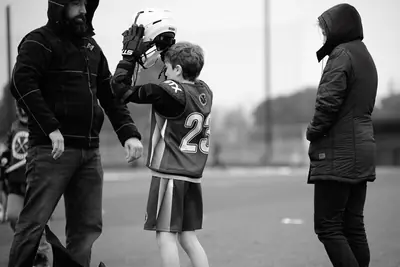 A young player gets high fives from his parents at the field