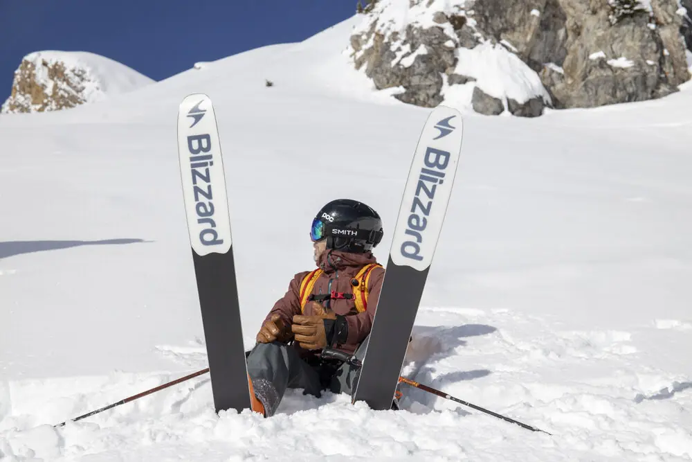 A skier buried to the chest in powder, skis planted upright